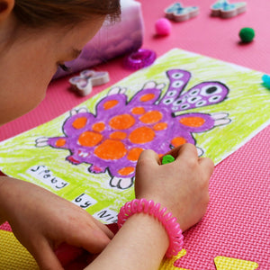 Candy Pink SpiraBobble on wrist of a child who is drawing a picture