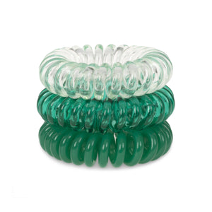 A tower of 3 clearly green coloured hair bobbles called spirabobbles. A clear and green plastic spiral circular hair tie spira bobble.