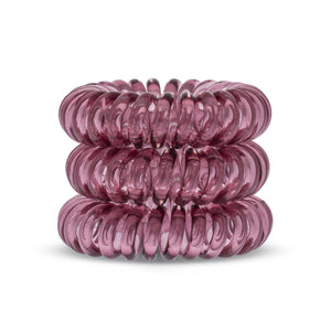 A tower of 3 maroon red coloured hair bobbles called spirabobbles. A red plastic spiral circular hair tie spira bobble