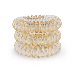 A tower of 3 light orange coloured hair bobbles called spirabobbles. An orange plastic spiral circular hair tie spira bobble.