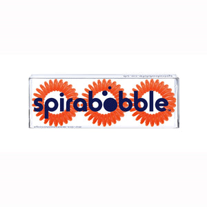 A flat transparent box of 3 bright orange coloured hair accessories called spirabobbles