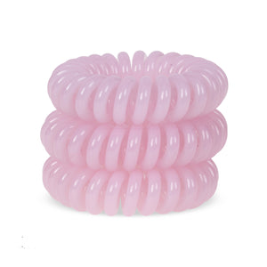 A tower of 3 baby pink coloured hair bobbles called spirabobble. A plastic spiral circular hair tie spira bobble.