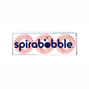 A flat transparent box of 3 barely red coloured hair accessories called spirabobbles