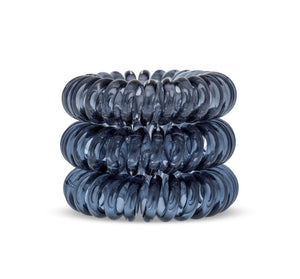 A tower of 3 black coloured hair bobbles called spirabobbles. A clear black plastic spiral circular hair tie spira bobble.