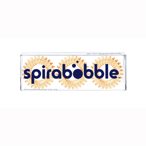 A flat transparent box of 3 light orange coloured hair accessories called spirabobbles