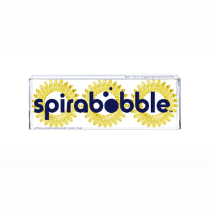 A flat transparent box of 3 mellow yellow coloured hair accessories called spirabobbles