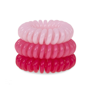 A tower of 3 pretty in pink different coloured hair bobbles called spirabobbles. A plastic spiral circular hair tie spira bobble.
