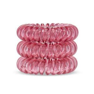 A tower of 3 simply cerise pink coloured hair bobbles called spirabobbles. A plastic spiral circular hair tie spira bobble.