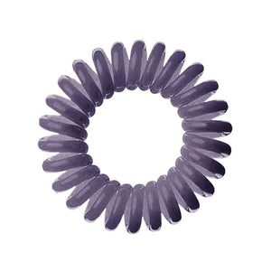 A dark grey solid coloured plastic circular hairband on a white background that looks like an old fashioned curly coiled telephone cable or a coiled spring which has been made into a circular shape