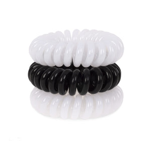 A tower of 3 black and white coloured hair bobbles called spirabobbles. A plastic spiral circular hair tie spira bobble.