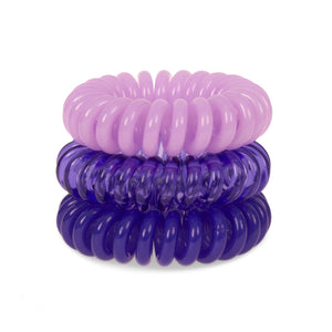 A tower of 3 purple different coloured hair bobbles called spirabobbles. A plastic spiral circular hair tie spira bobble.