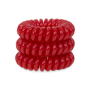 A tower of 3 red coloured hair bobbles called spirabobbles. A plastic spiral circular hair tie spira bobble.