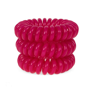 A tower of 3 rose pink coloured hair bobbles called spirabobbles. A plastic spiral circular hair tie spira bobble.